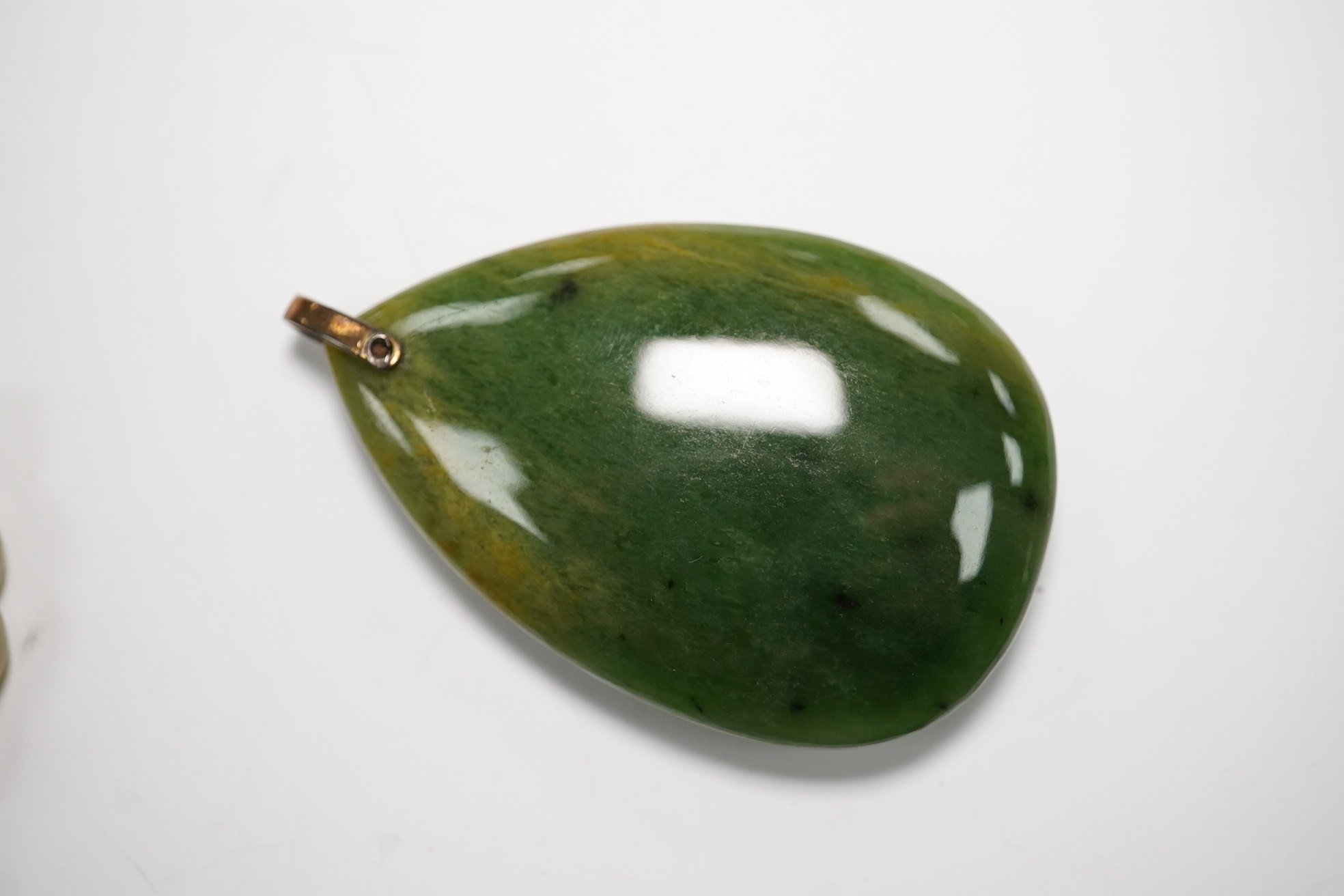 Two jade pendants including a carved example and a jade marquise ring, largest 6.5cm wide. Condition - fair to good